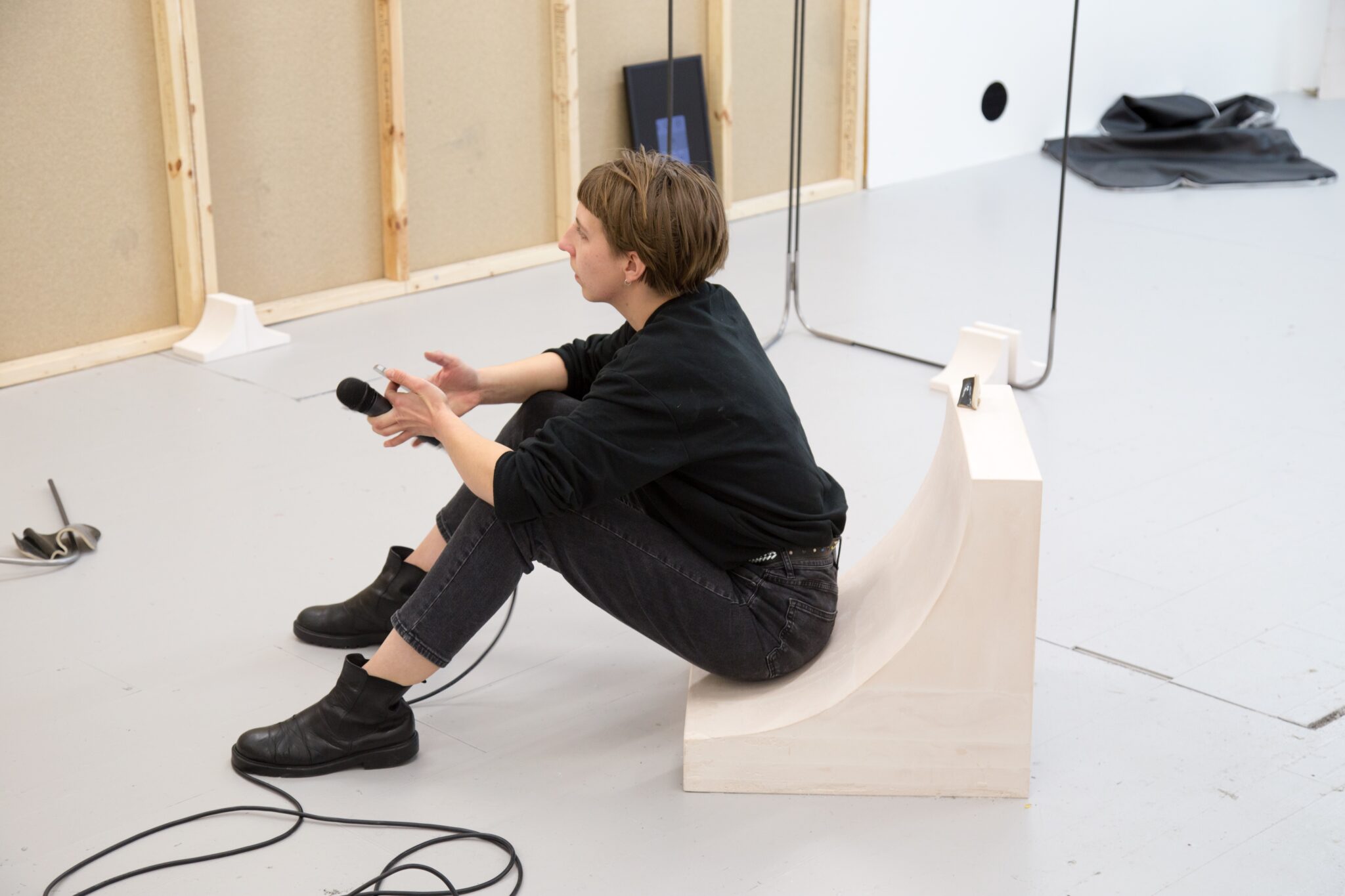 Julia sitting on a wooden curved block using electronics